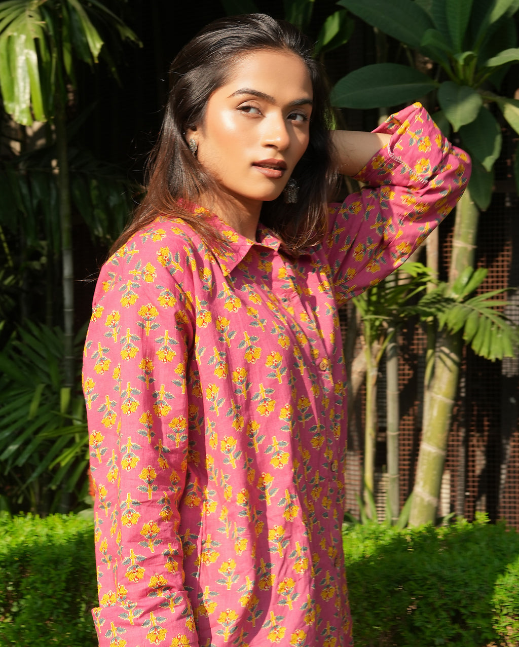 Woman wearing a Gulnaar shirt standing outdoors with greenery in the background