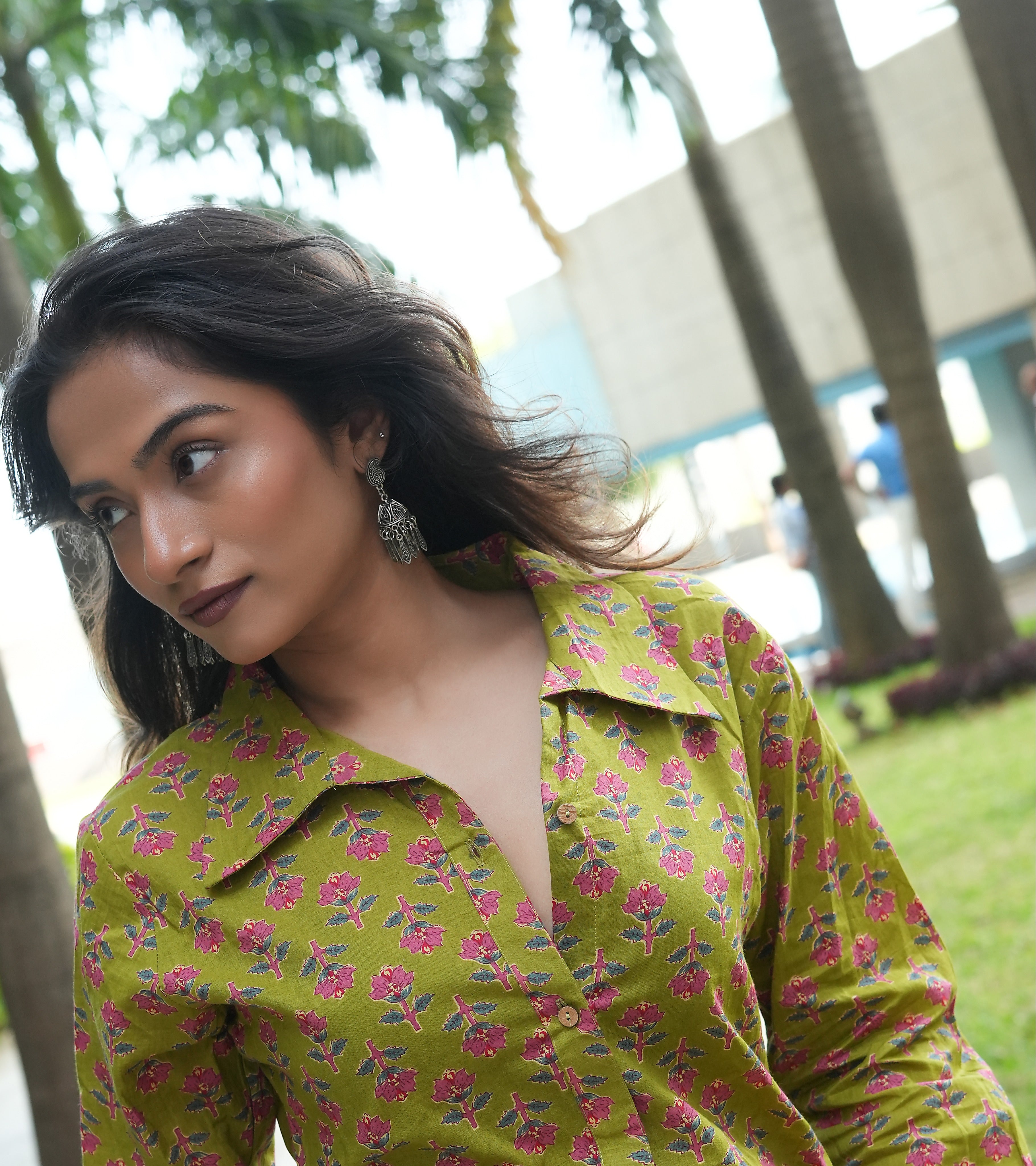 Woman wearing a Phoolwari shirt outdoors with trees and buildings in the background
