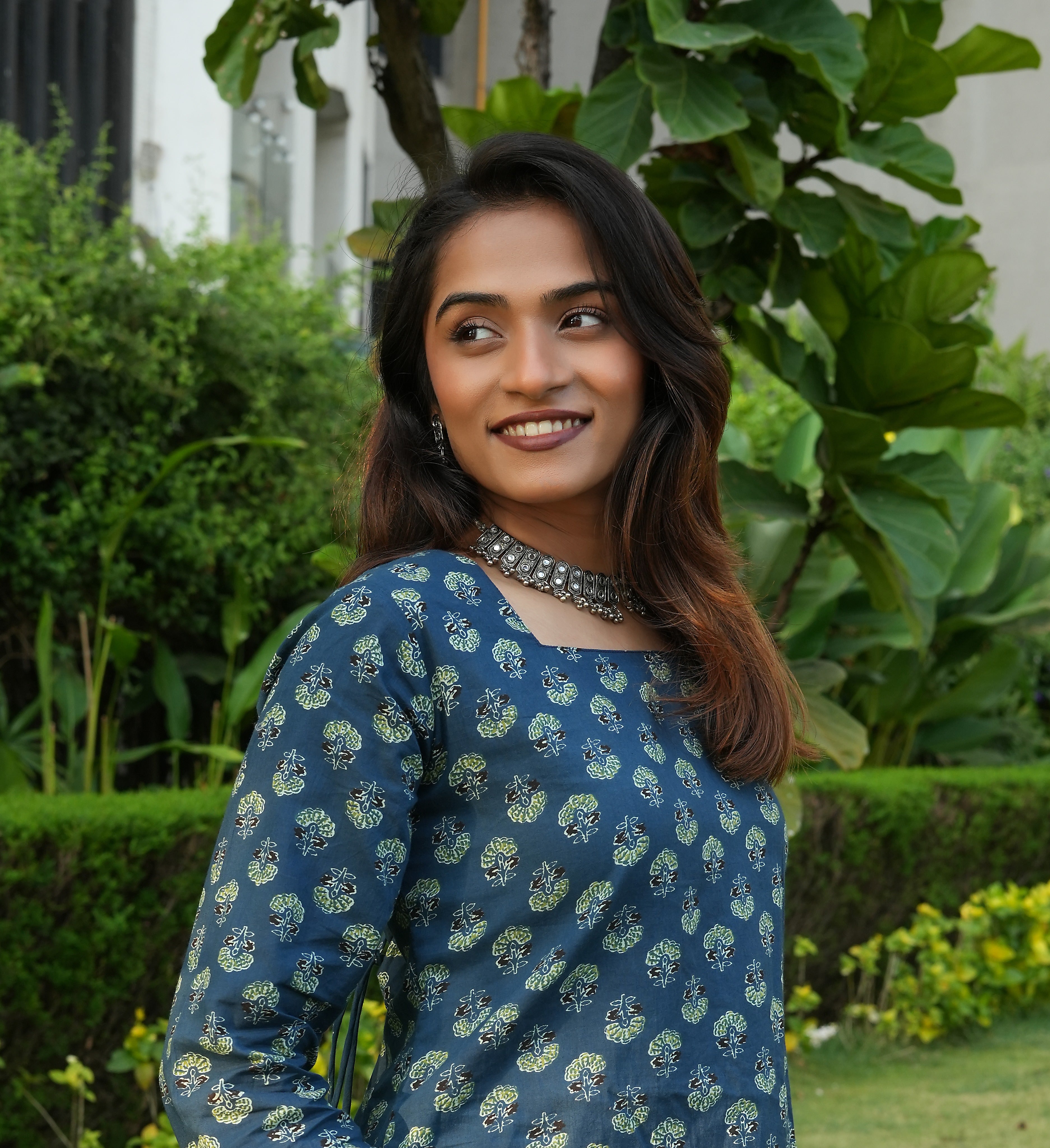 Woman wearing a Teal lace up Kurti outfit standing in a garden
