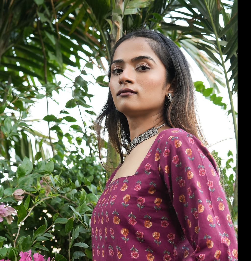 Woman in a Wine blossom kurti standing among green foliage