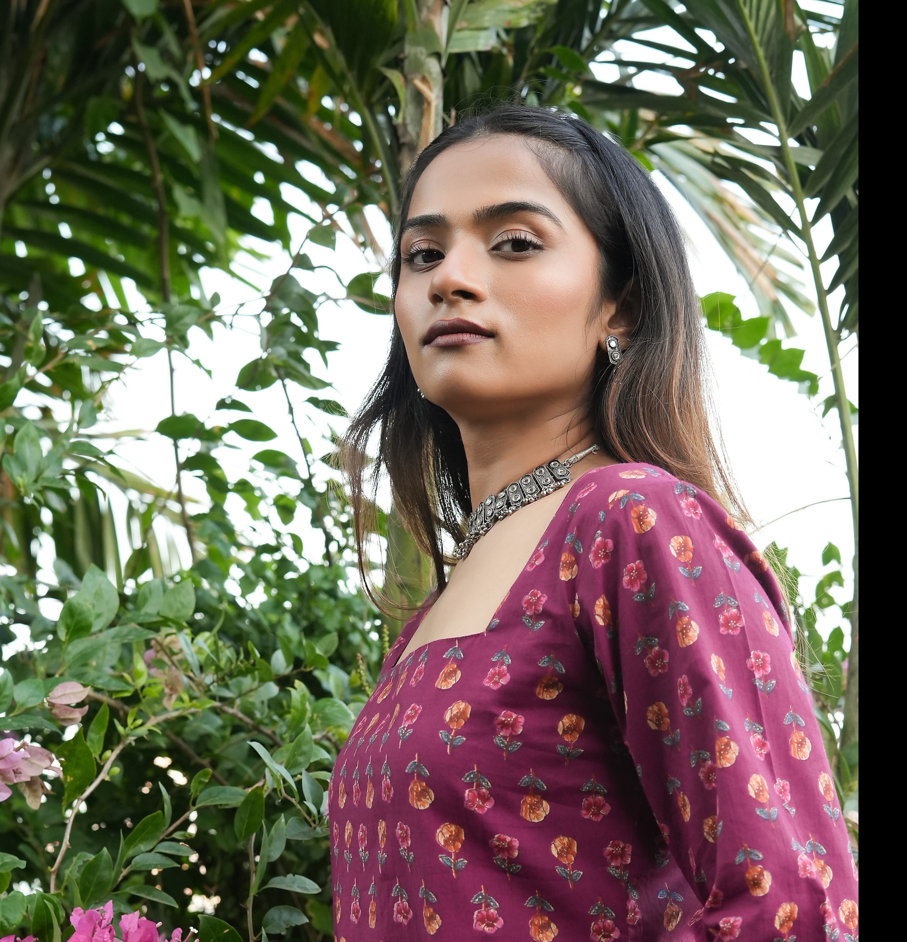 Woman in a Wine blossom kurti standing among green foliage