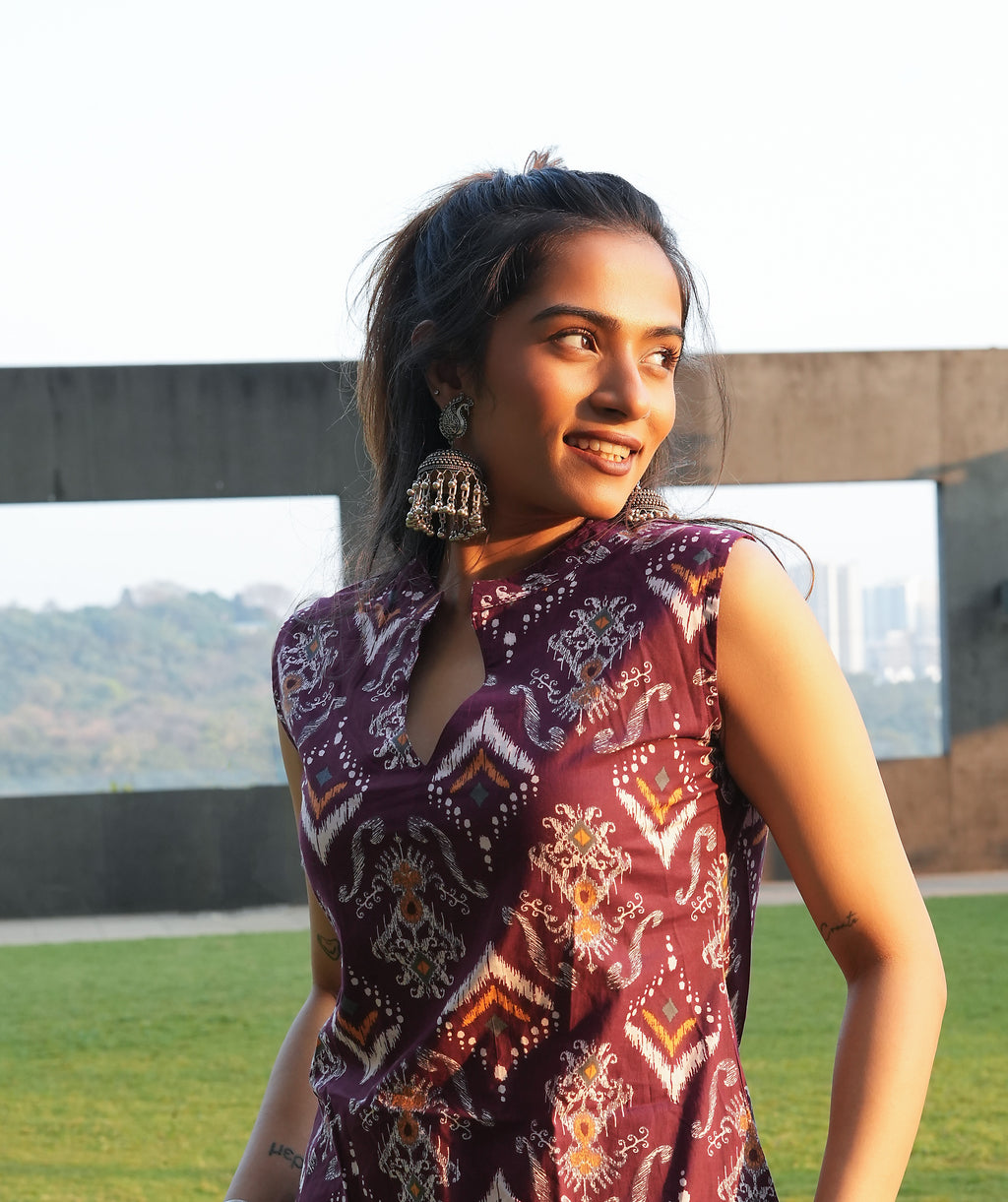 Woman wearing a Maroon ikat kurti dress with a scenic background