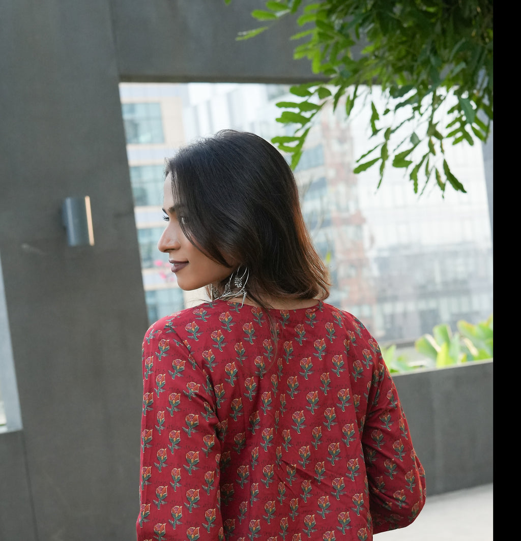 Woman wearing a Laal kurta standing in front of a window with greenery