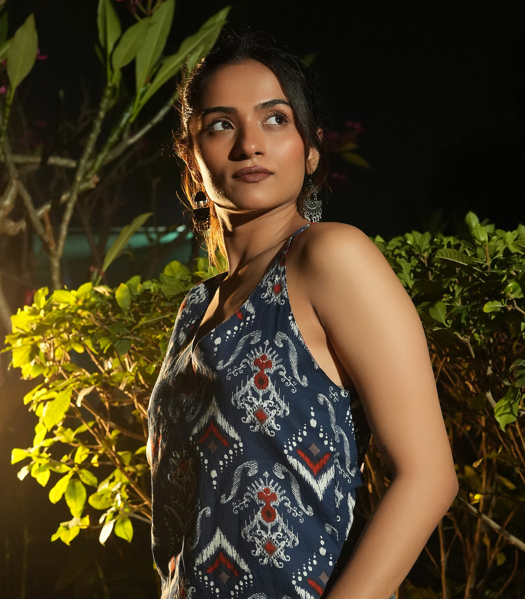 Woman wearing aNeel ikat kurta standing among green plants at night.