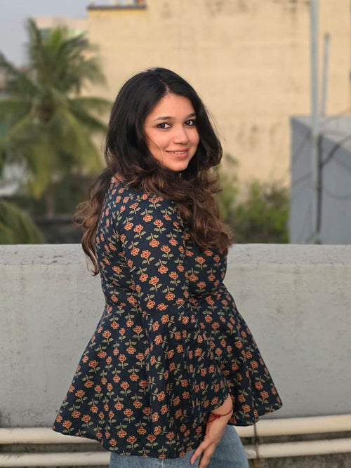 Woman standing on a rooftop with a building and palm trees in the background